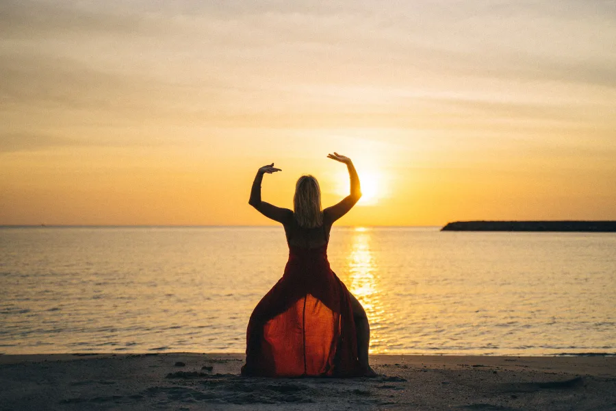Silhouette with arms raised on a beach at sunset